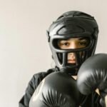 A focused young martial artist wearing protective helmet and gloves, ready to train. Indoors setting.