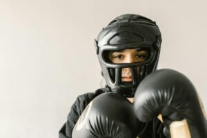 A focused young martial artist wearing protective helmet and gloves, ready to train. Indoors setting.